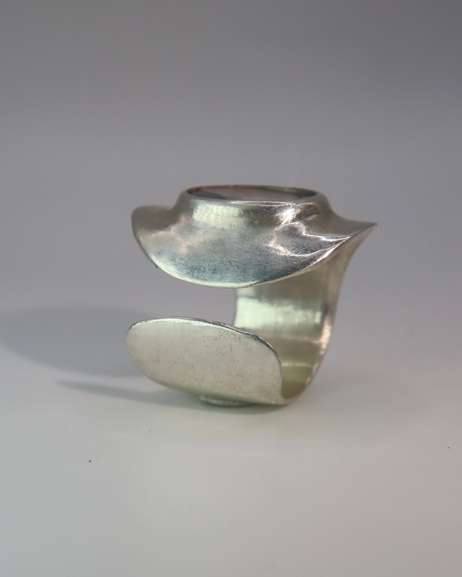 Silver ring with a unique design on a gray background