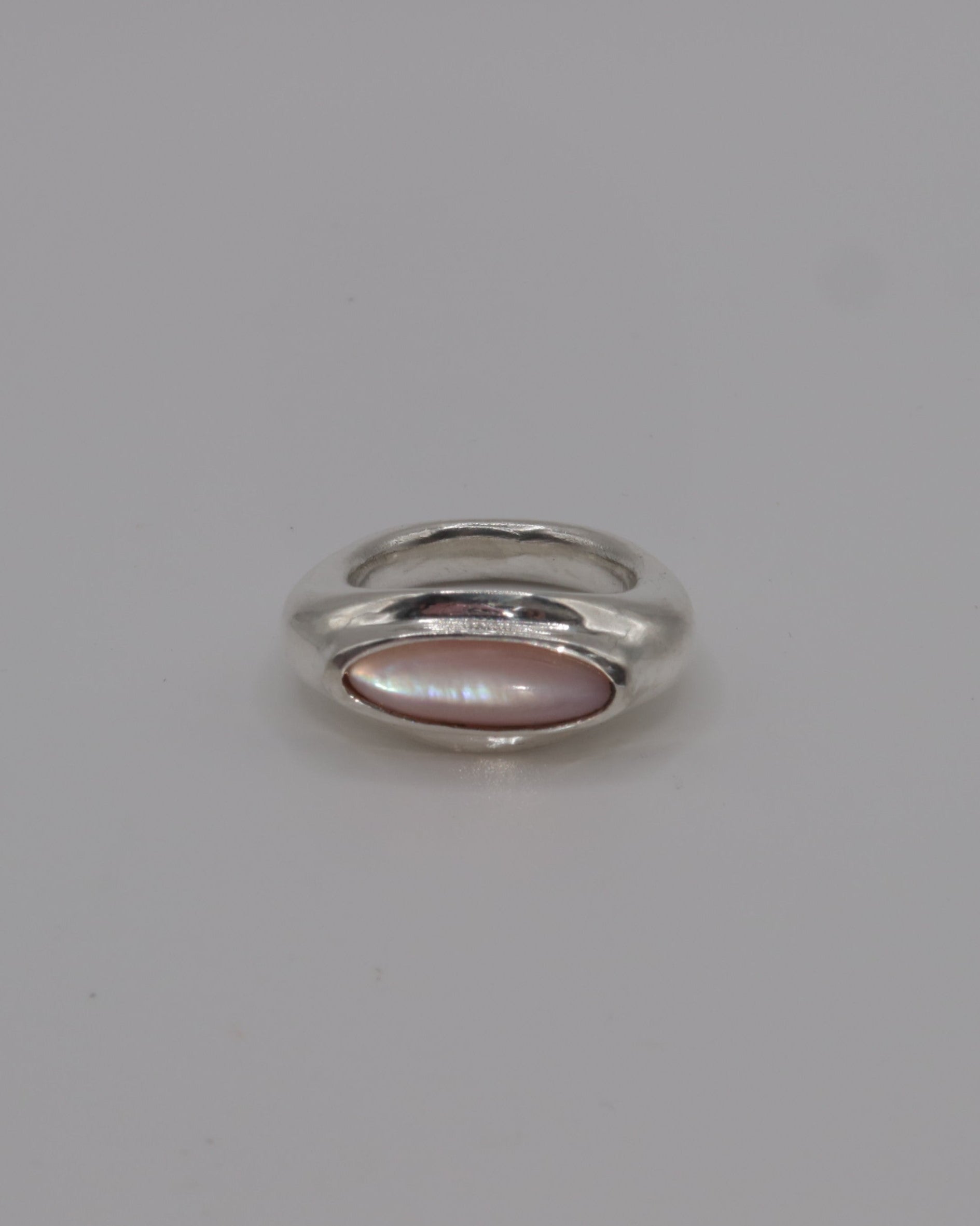 Small silver ring with a pink stone on a light gray background